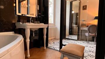Une salle de bain moderne avec une grande baignoire, un meuble-lavabo avec un miroir et une chaise au premier plan.