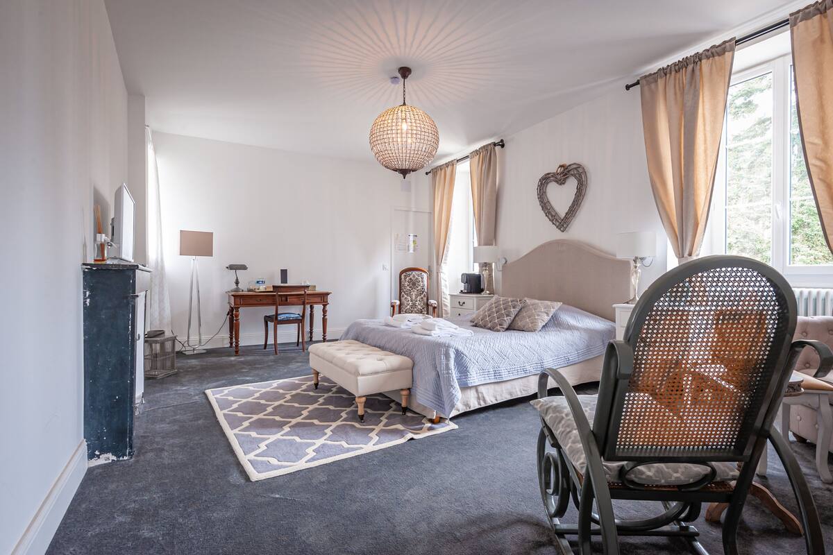 A bedroom with a bed, a desk, a chair, a dresser, and a window with curtains.
