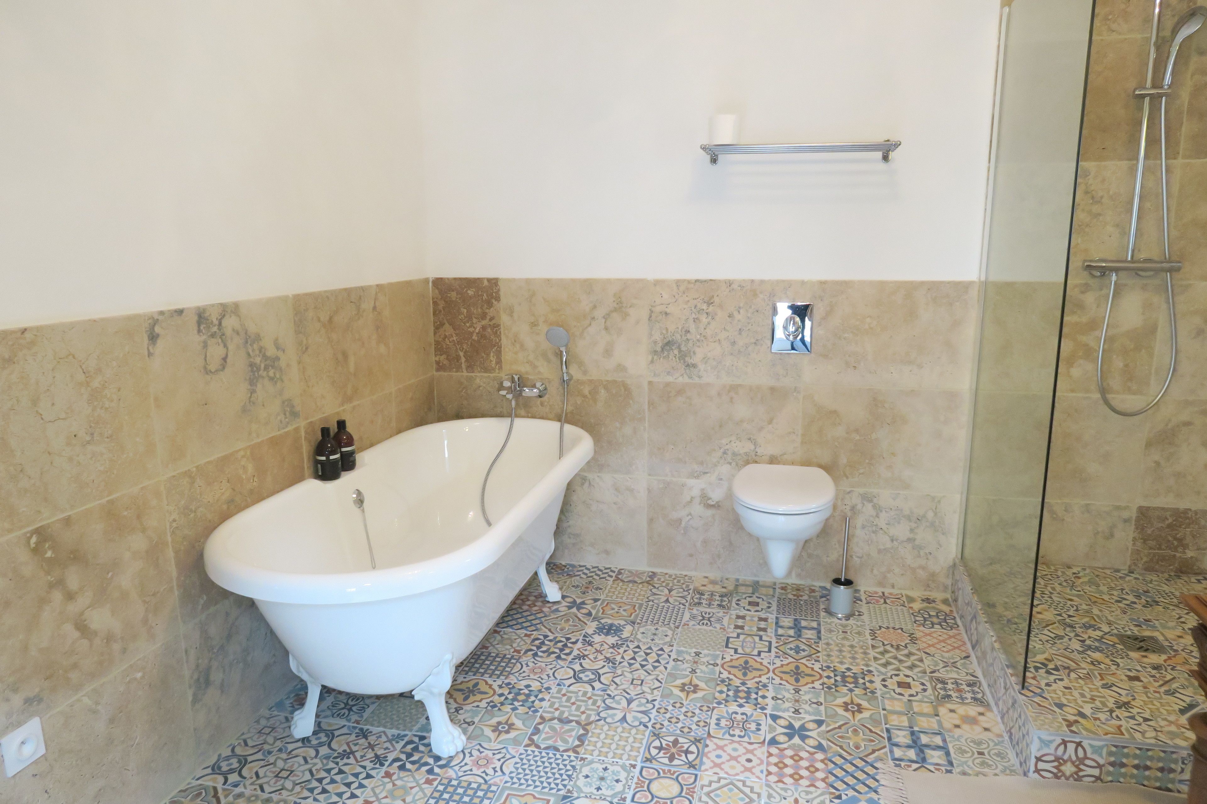 A bathroom with a freestanding bathtub, a toilet, and a shower area.