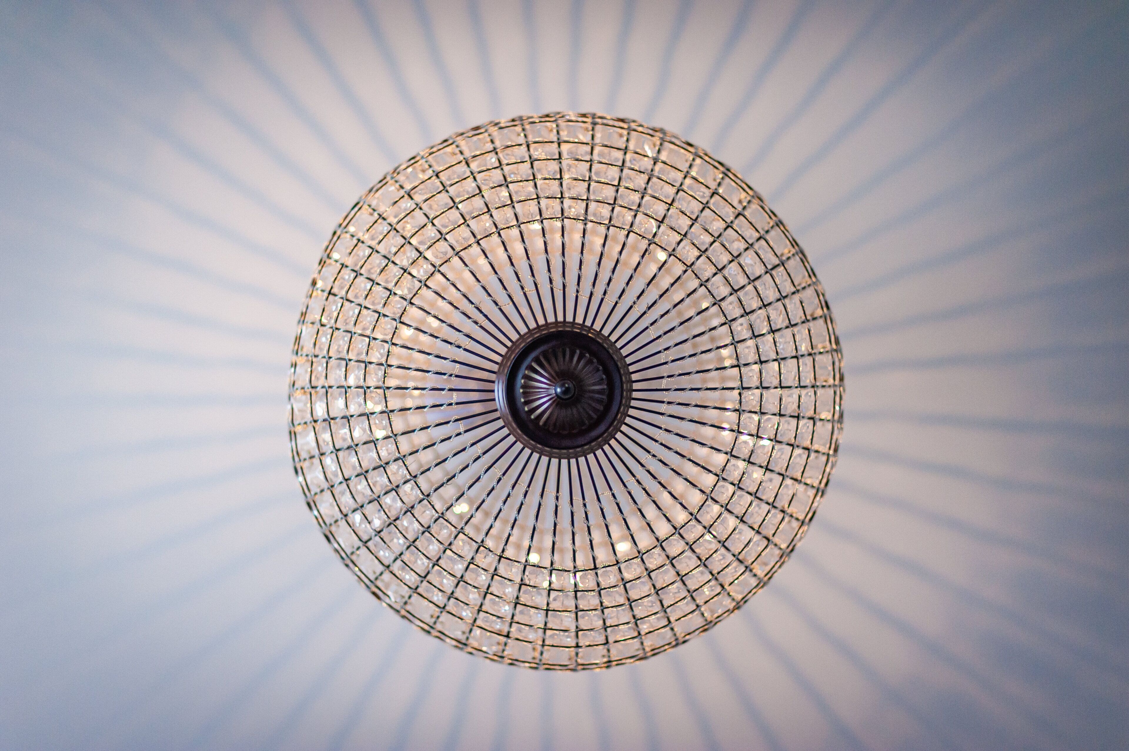 A circular chandelier with a grid pattern and a central light fixture.