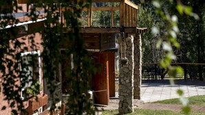 A rustic building with a stone pillar, wooden deck, and a wooden door. - Equs Posada de Campo (San Carlos de Bariloche)
