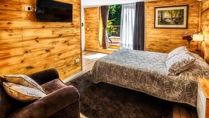 A wooden cabin-style bedroom with a bed, a couch, and a TV. - Equs Posada de Campo (San Carlos de Bariloche)