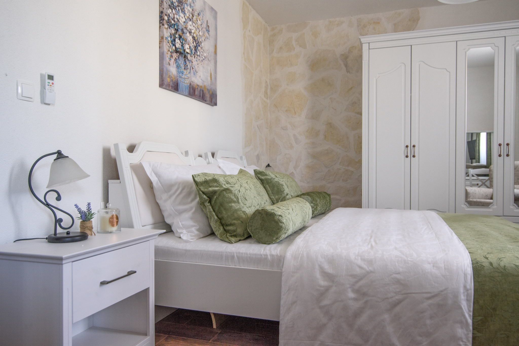 Un dormitorio con una cama, una mesita de noche, una lámpara, un cuadro y un armario.