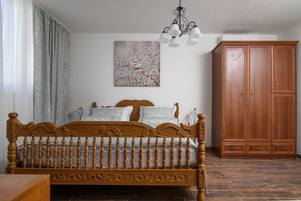 A bedroom with a wooden bed, a wardrobe, and a painting on the wall.