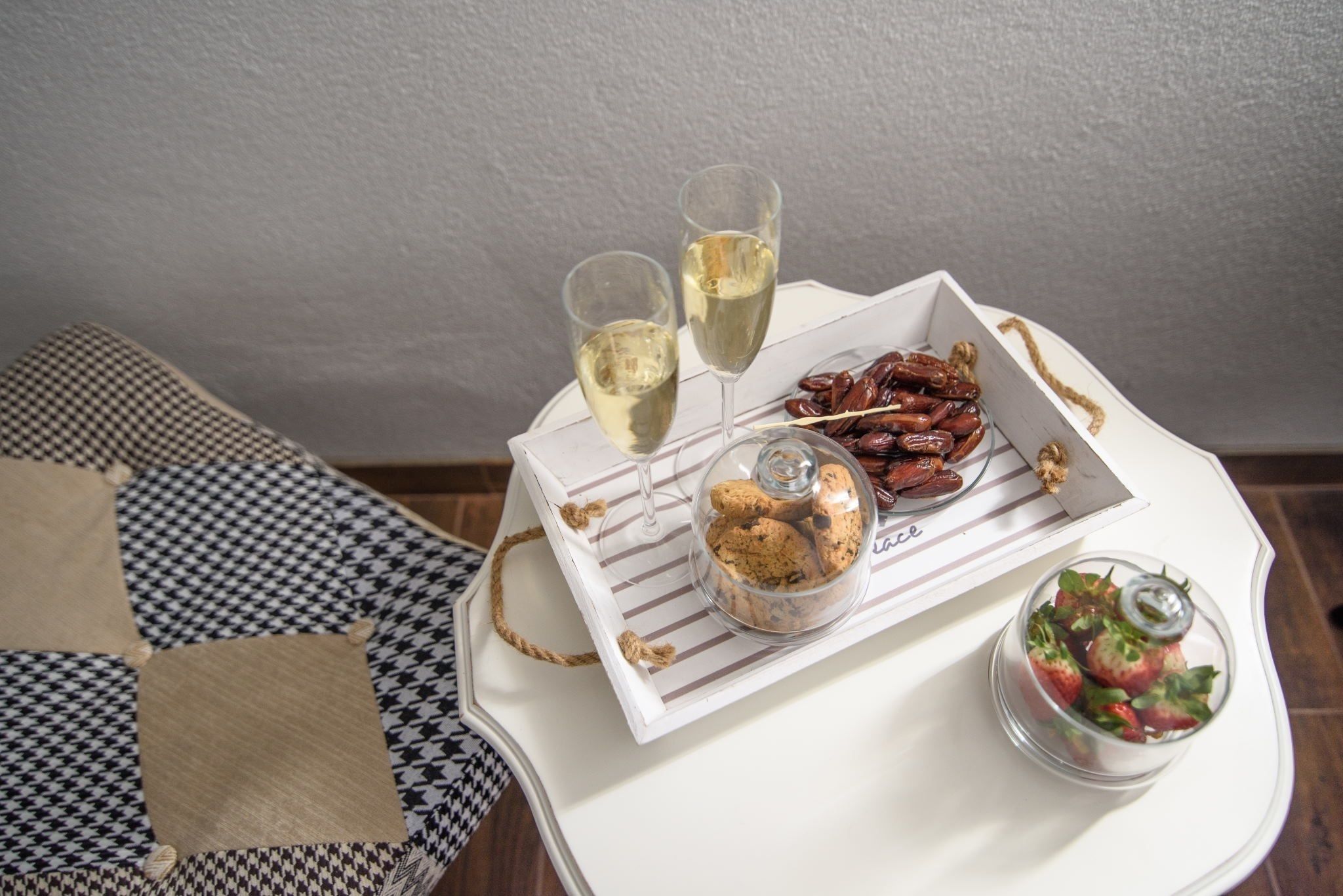 A tray with cookies, a glass of white wine, and a glass of rosé wine on a white table.
