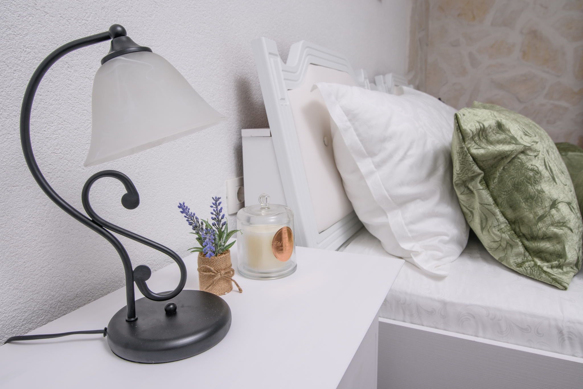 Une table de chevet avec une lampe, une bougie et une petite plante.