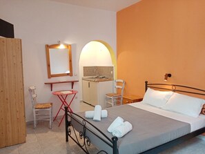 A bedroom with a bed, a small table, a chair, a mirror, and a wardrobe. - Depis Apartments 2 (Naxos)