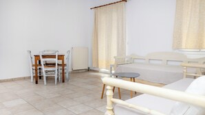 A bedroom with a bed, a small table, a chair, and a radiator. - Depis Apartments 2 (Naxos)