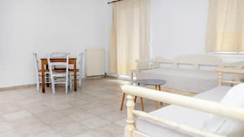 A bedroom with a bed, a small table, a chair, and a radiator.