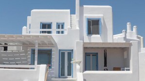 A white building with blue-framed windows and doors, a staircase, and a small balcony. - Depis Sea Side Villas (Naxos)