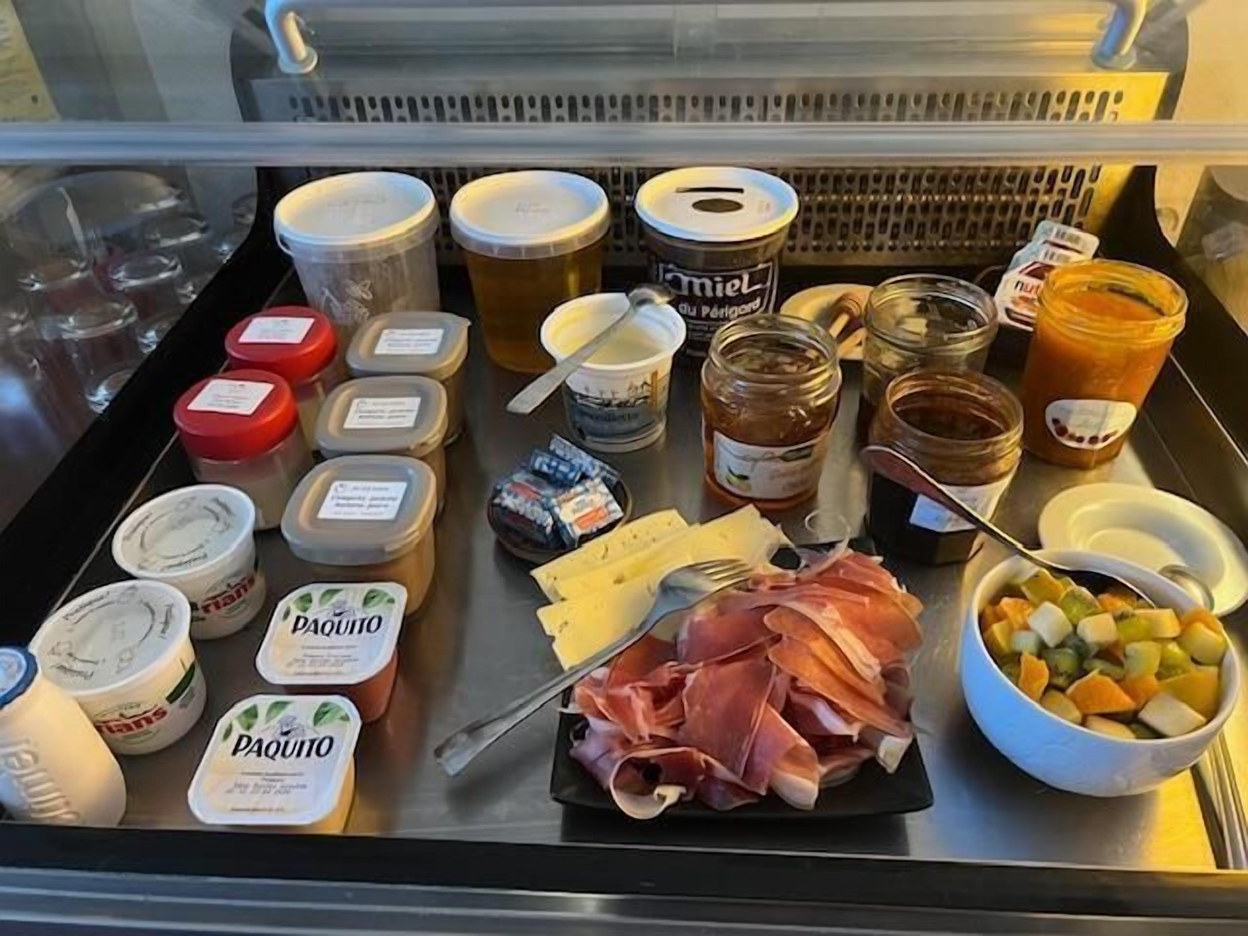 Un bufé de desayuno con diversos alimentos, incluyendo carnes, quesos y salsas.