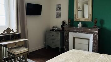 A bedroom with a bed, dresser, vanity, and a fireplace.