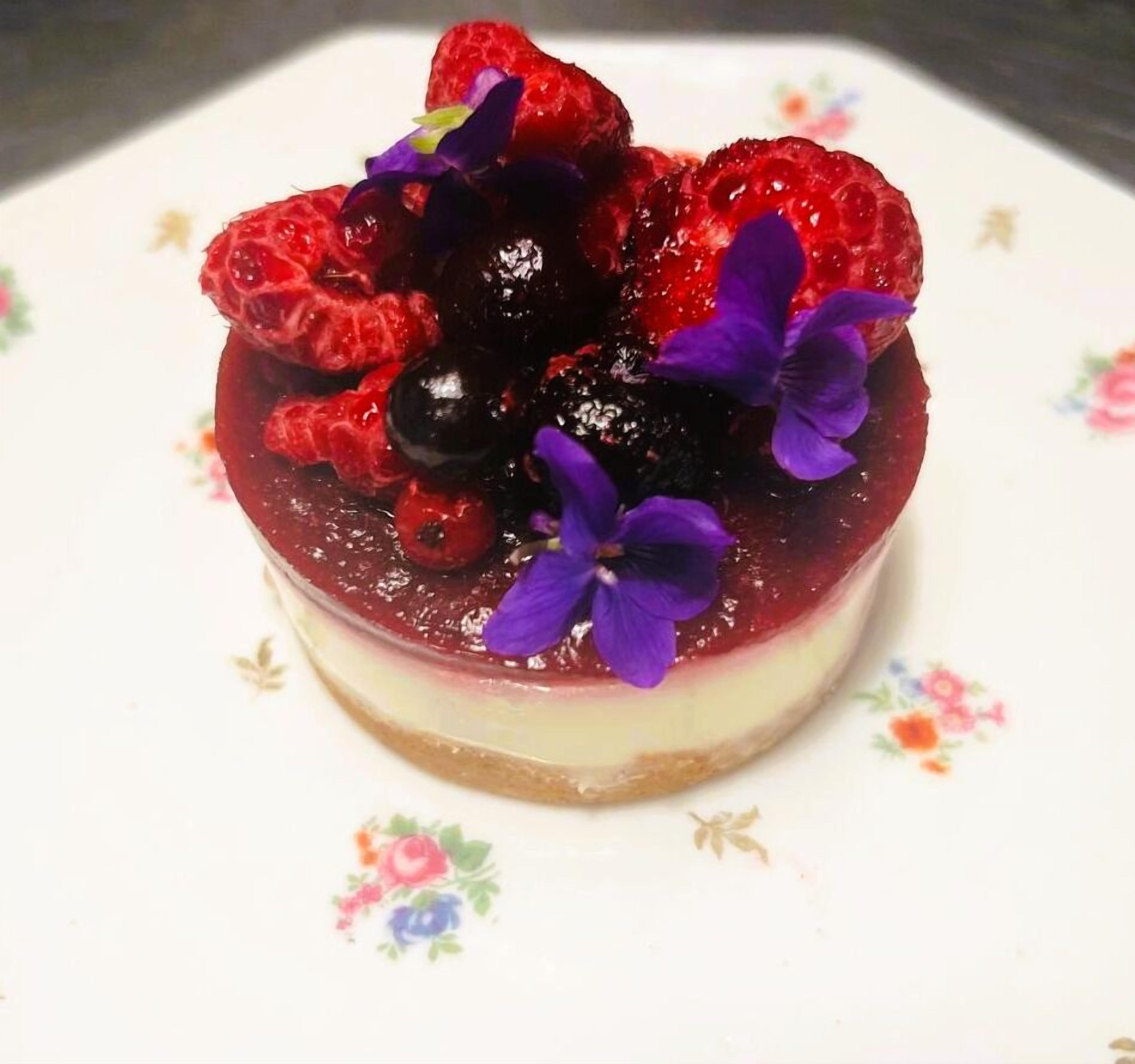 Ein Dessert mit Beeren und Blüten auf einem Teller.