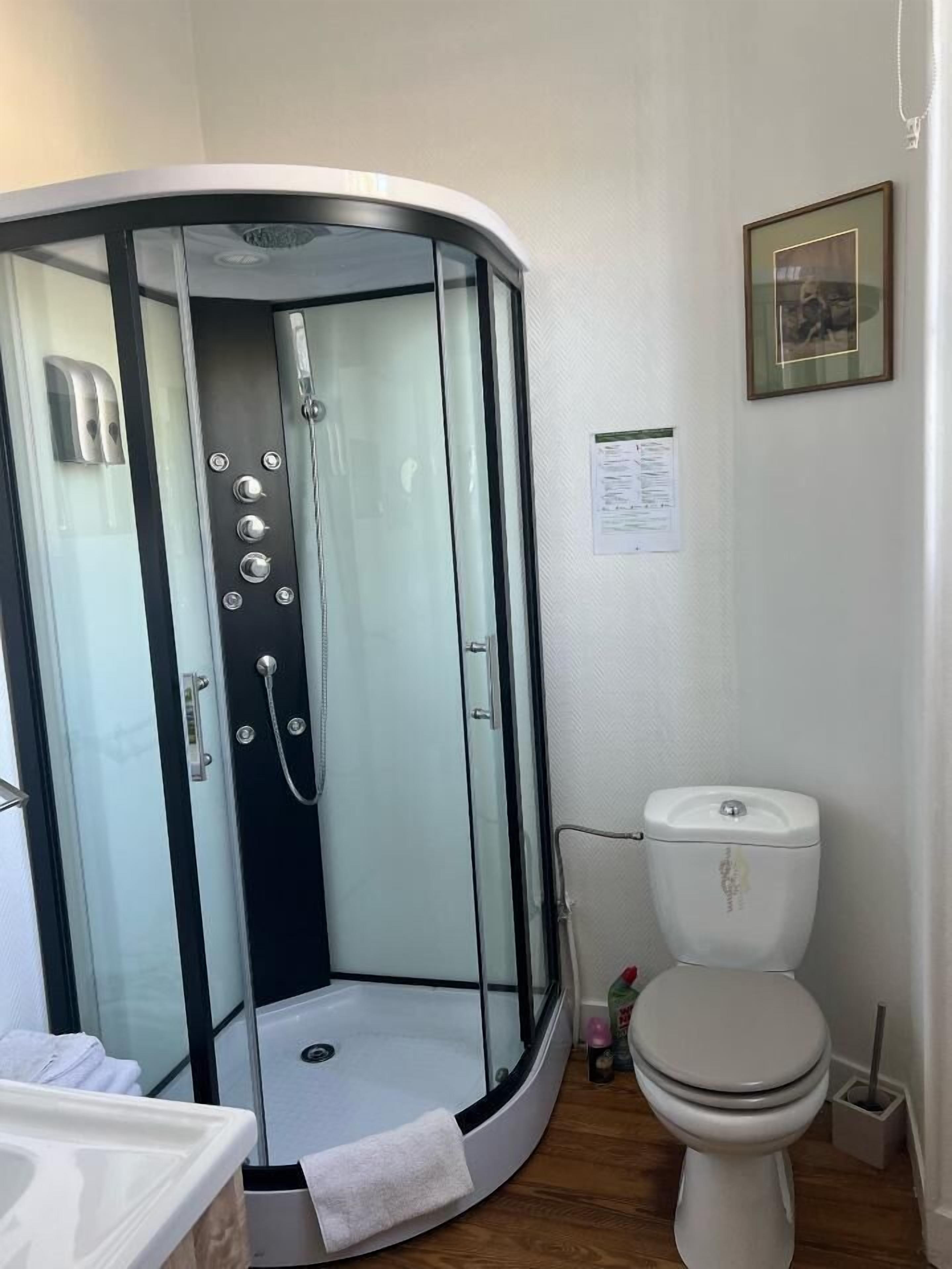 A modern bathroom with a glass-enclosed shower, a toilet, and a sink.