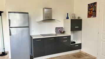 Uma cozinha compacta com geladeira de aço inoxidável, fogão moderno e armário com gavetas.