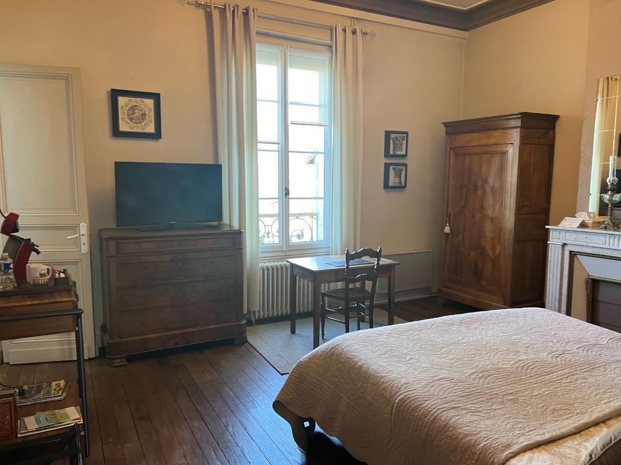 Una habitación con cama, escritorio, cómoda y televisor.