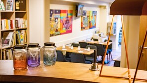 Una habitación con una mesa de madera que muestra tres tarros de vidrio con tapas, un candelabro de metal y una estantería llena de libros.