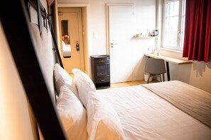 A hotel room with a bed, a desk, a chair, a heater, and a door. - Hôtel Aigle d'Or (Reichstett)