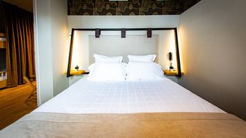 A neatly made double bed with a headboard, bedside tables with lamps, and a small potted plant on each side.