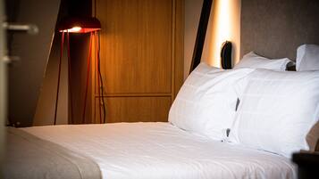 Quarto de hotel com uma cama bem arrumada, um guarda-roupa de madeira e um abajur.