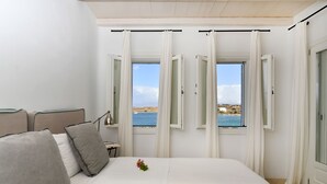 Un dormitorio con cama, mesita de noche y vista al mar.