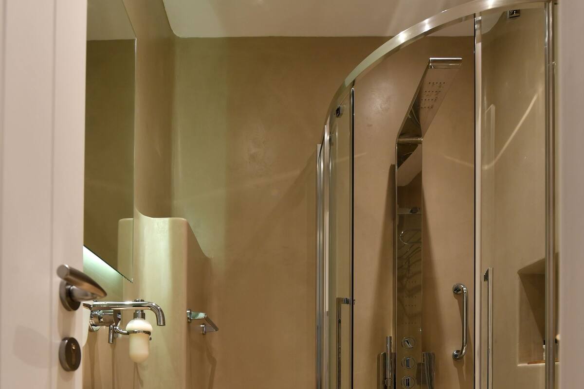 A modern bathroom with a large beige sink, a glass-enclosed shower, and a walk-in shower.