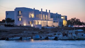 Un edificio costero con varios balcones y un espacio al aire libre techado. Barcos amarrados al frente.
