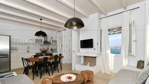 Una sala de estar moderna con comedor, chimenea y televisor montado en la pared.