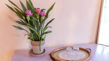A potted plant with pink flowers on a table next to a tray with a glass and a small container.