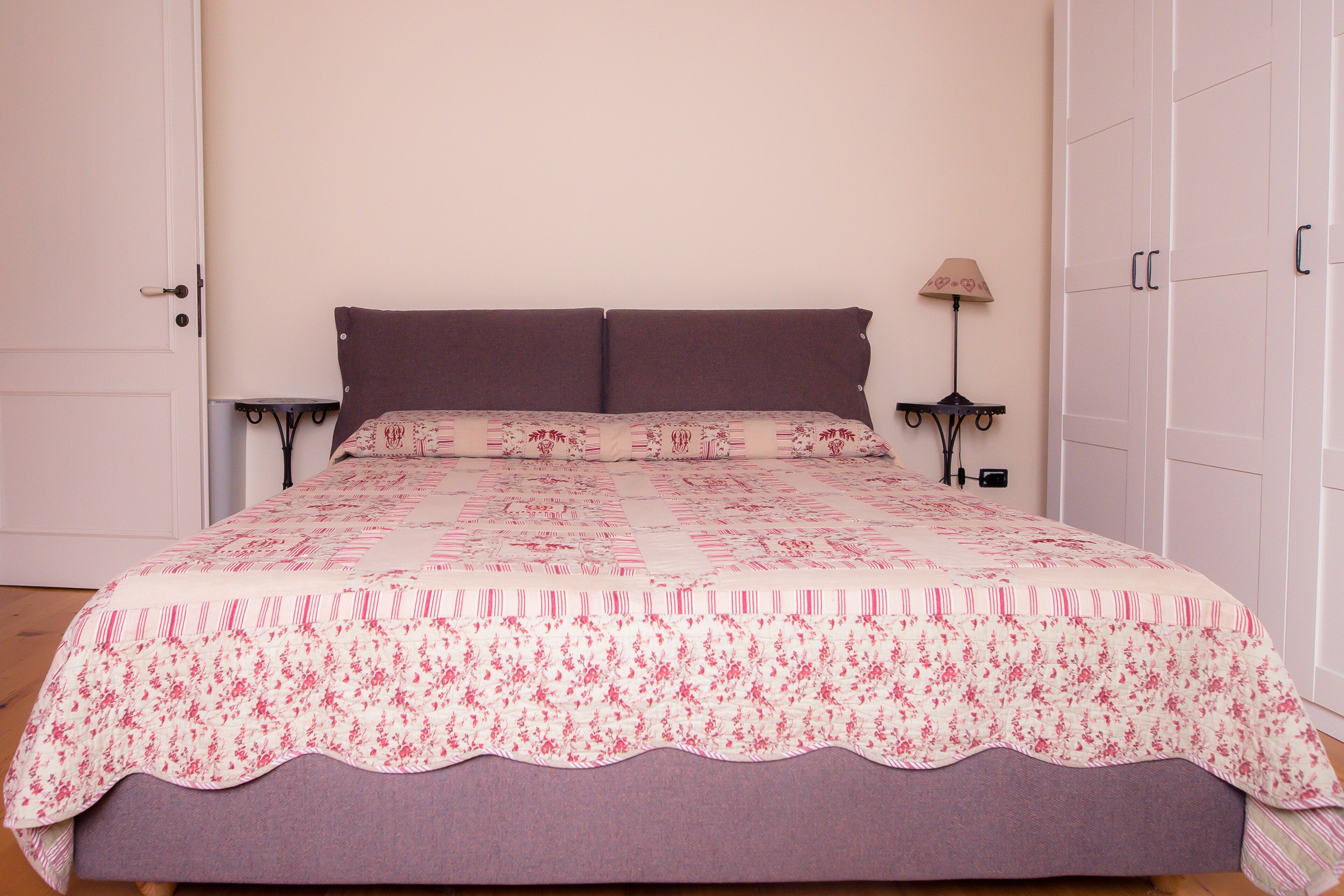 Une chambre à coucher avec un lit, une table de chevet, une lampe et une armoire.