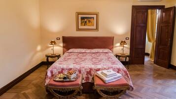 A hotel room with a large bed, two bedside tables with lamps, a picture on the wall, and a wooden door.