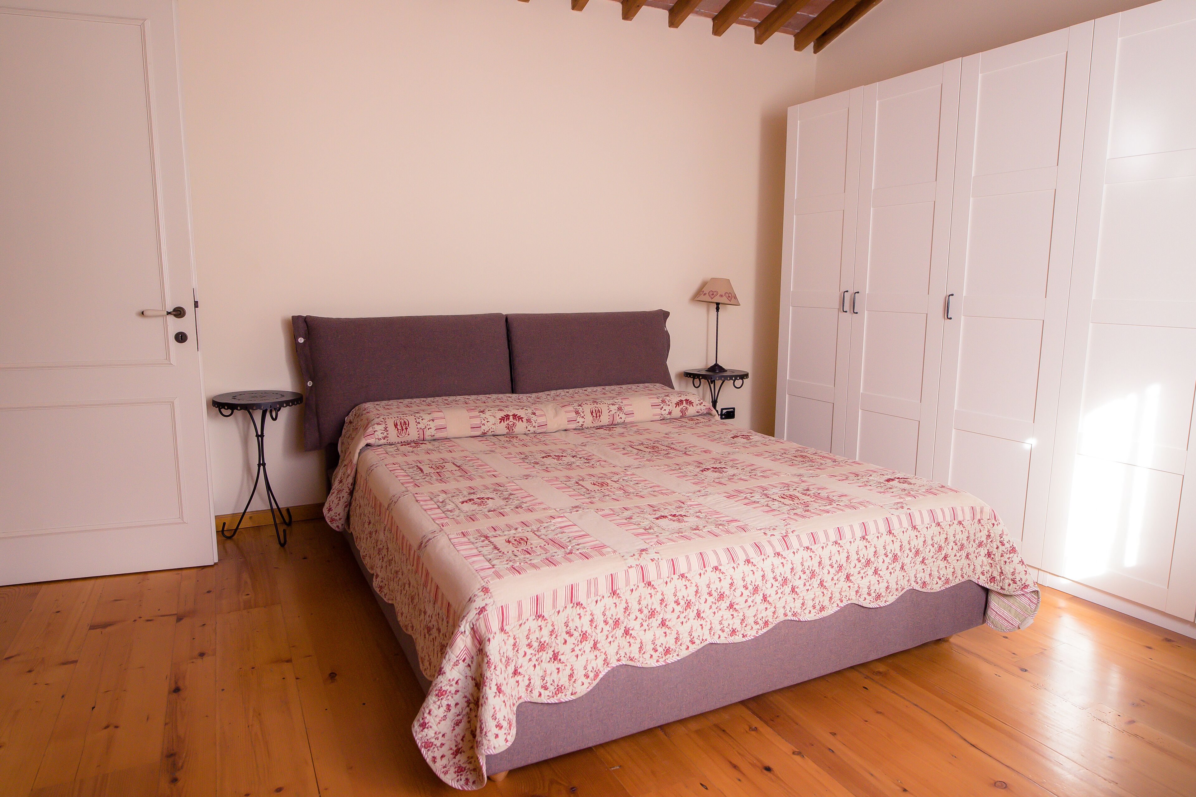 Une chambre à coucher avec un lit, une armoire et une table de chevet avec une lampe.