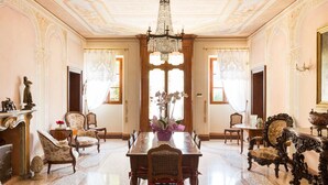 A spacious dining room with ornate furniture, a chandelier, and large windows. - Villa Nichesola (Colognola ai Colli)