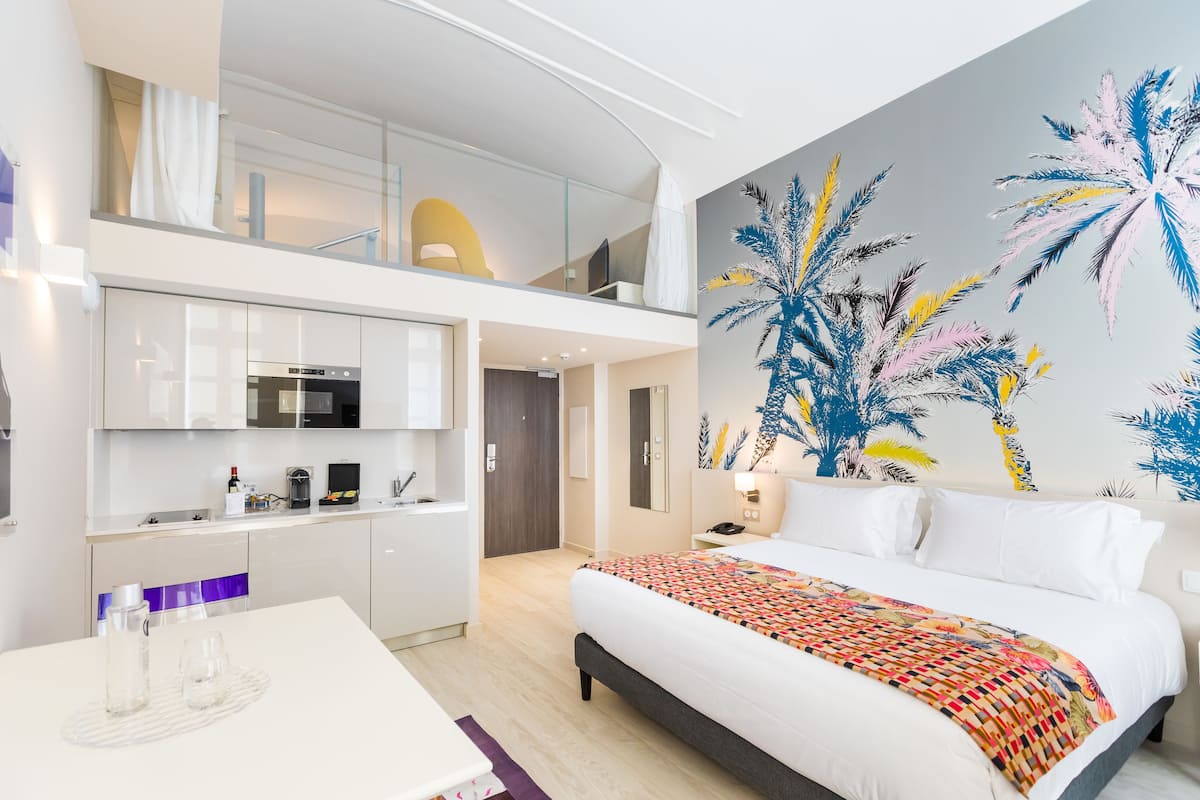 Une chambre d’hôtel moderne dotée d’un grand lit, d’une kitchenette et d’un balcon.