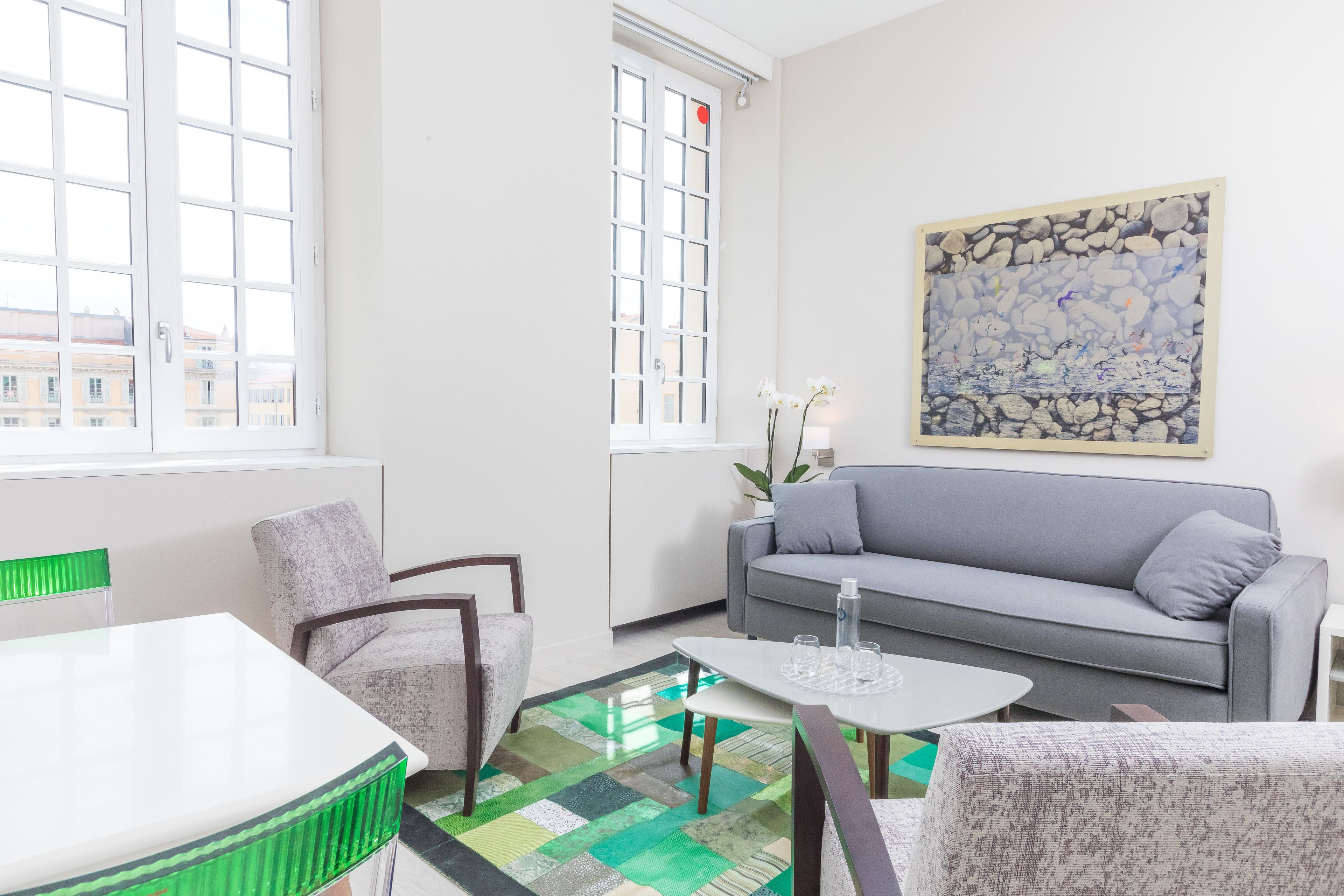 A modern living room with a grey sofa, a white coffee table, and a patterned rug.