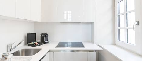 Une cuisine moderne avec des meubles blancs, un évier en acier inoxydable et une fenêtre offrant une belle vue.