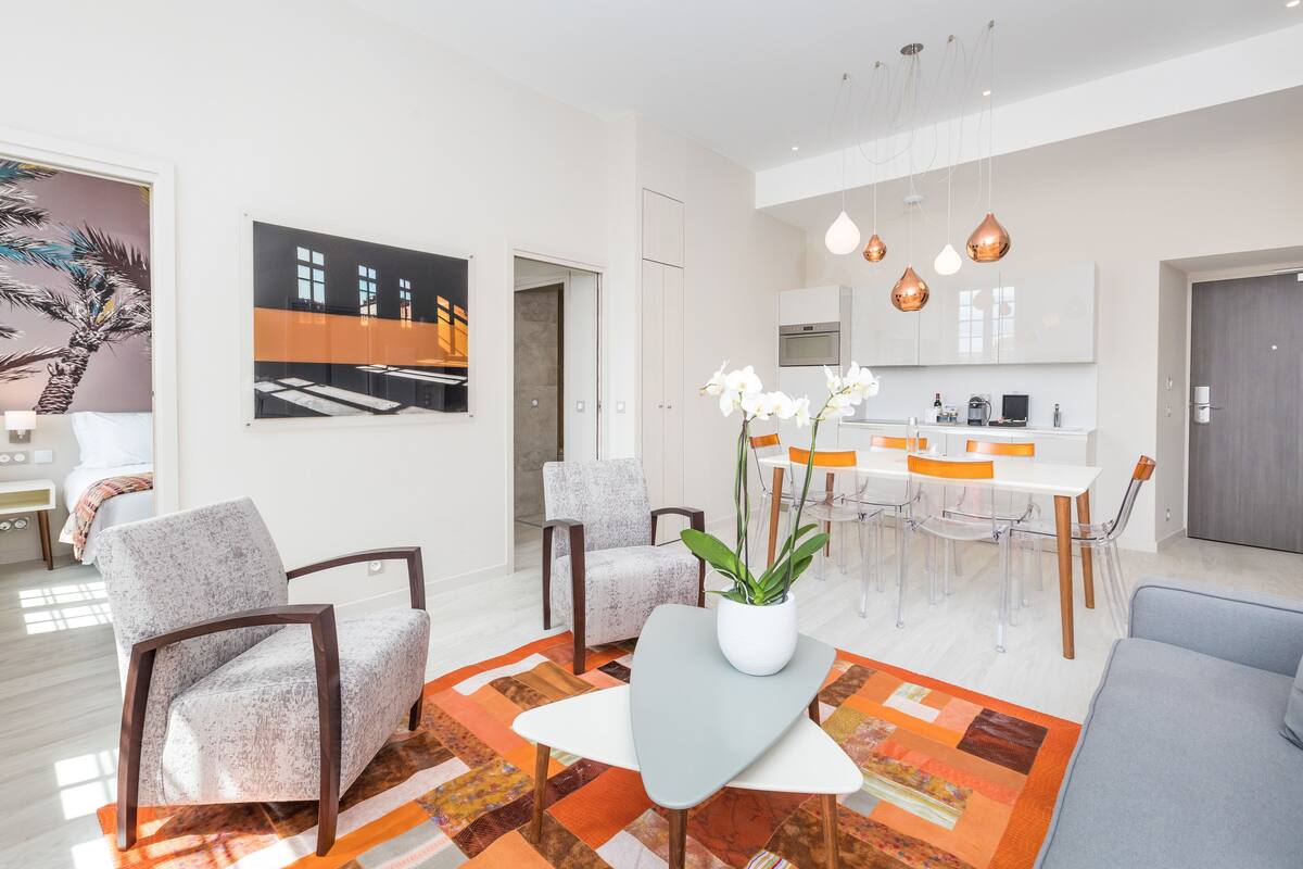 Un salon moderne comprenant un canapé, des fauteuils, une table basse et un coin repas avec des chaises et une table.