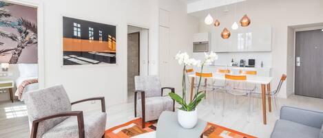 Una sala de estar moderna con un sofá, sillones, una mesa de centro y un comedor con sillas y una mesa.