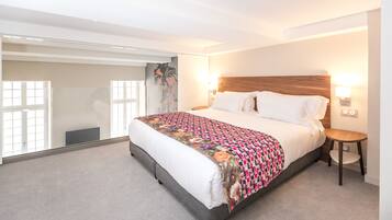 A modern hotel room with a large bed, a small bedside table, and a view of the outside.