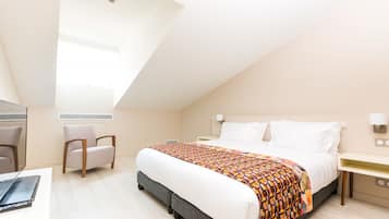 A modern hotel room with a large bed, a desk, a chair, and a skylight.