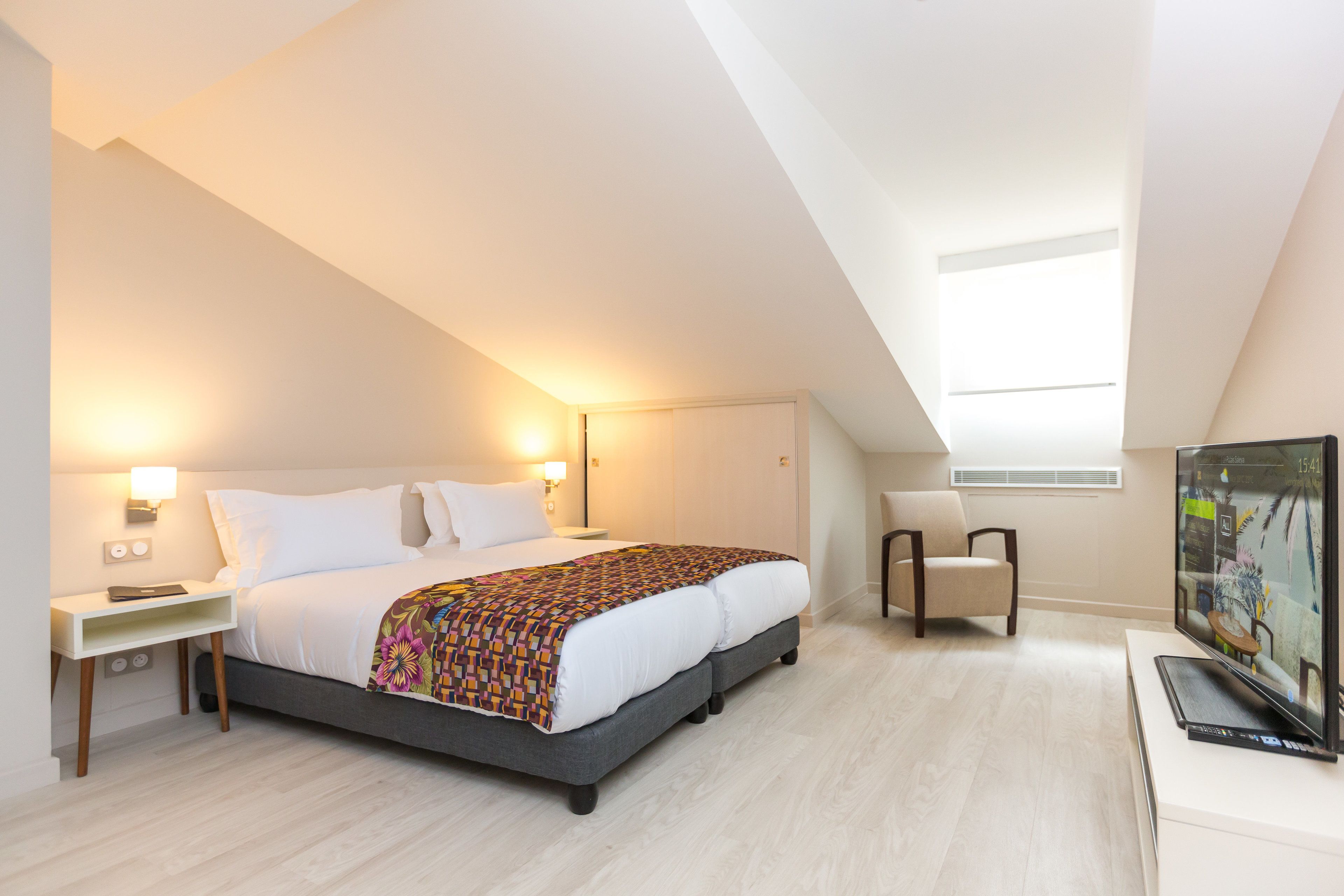 Une chambre d’hôtel moderne, dotée d’un grand lit, d’une télévision et d’un bureau.