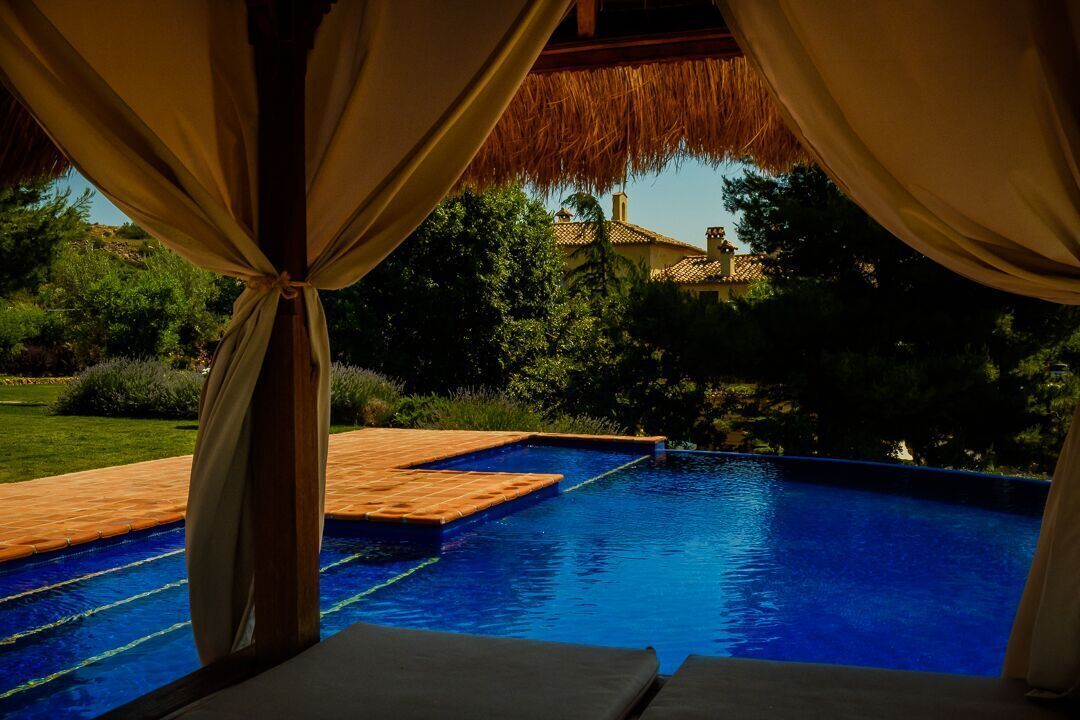 Una piscina al aire libre, una piscina infinita, sombrillas