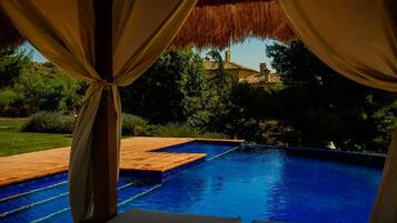 Una piscina al aire libre, una piscina infinita, sombrillas