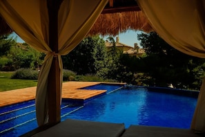Una piscina al aire libre, una piscina con borde infinito, sombrillas