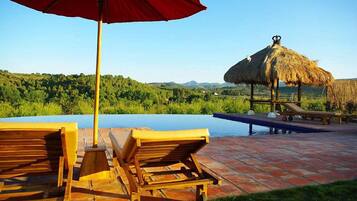 Een buitenzwembad, een infinity pool, parasols voor strand/zwembad