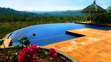 Una piscina al aire libre, una piscina infinita, sombrillas