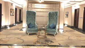 A hallway with two armchairs, a small table, and a marble floor. - Seven Garden AL wadi (Riyadh)