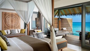 Une chambre dotée d’un grand lit, d’un coin salon avec vue sur l’océan et d’une décoration d’inspiration tropicale.