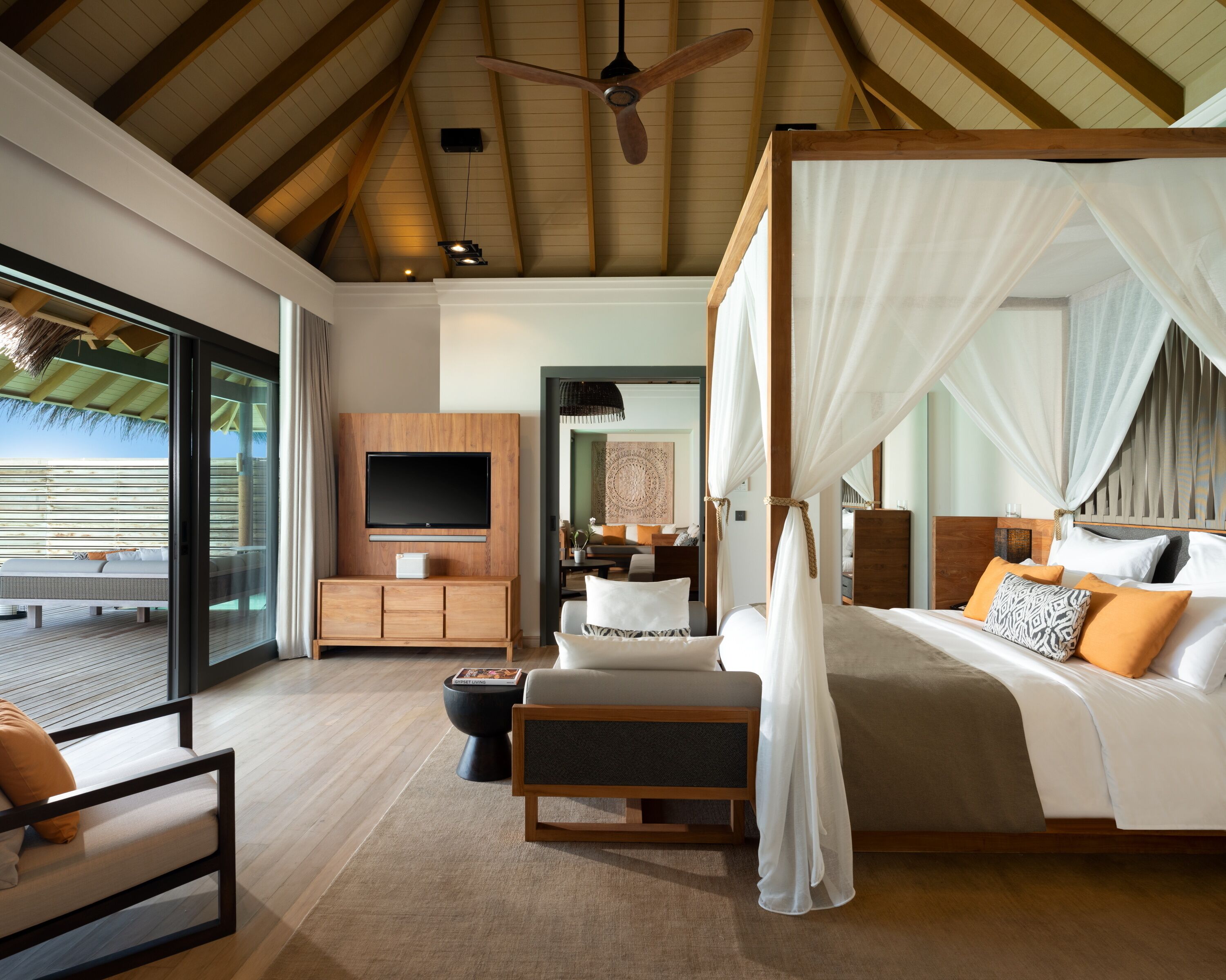 Un dormitorio espacioso con una cama grande, televisión, un armario de madera y un balcón con vistas.