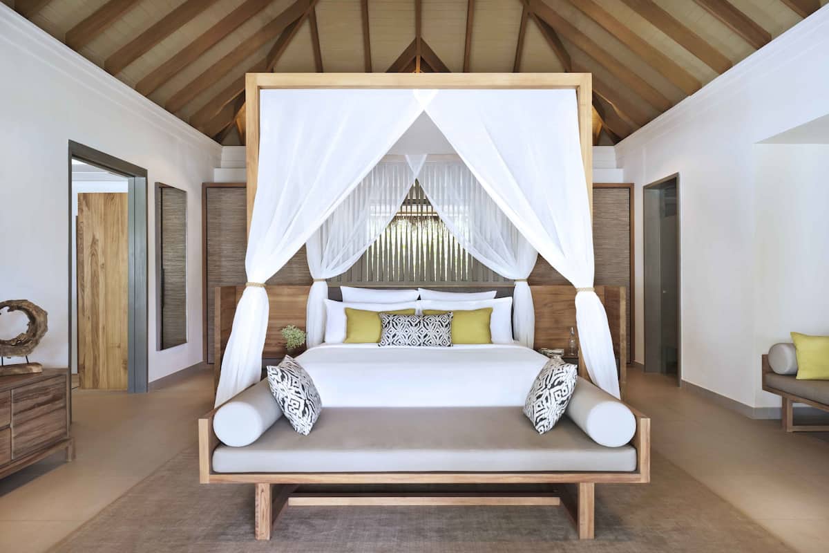 Un dormitorio amplio con una cama grande, cabecera de madera y dosel.